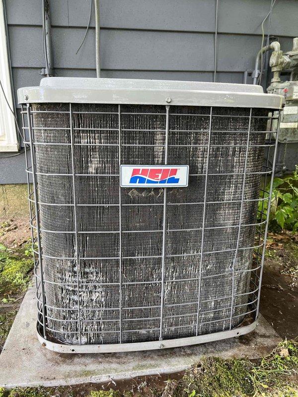 Completed annual cooling maintenance on 22-year-old Heil air conditioning system. Performed comprehensive tune-up inspection of outdoor condenser unit and indoor components. Found evaporator coil heavily contaminated with thick accumulation of dust, dirt, and debris causing significantly restricted airflow. Coil surface showed extensive buildup with matted and compressed fibrous material throughout the wire cage structure, indicating prolonged operation without proper maintenance. Outdoor condenser unit showed moderate soiling of fins and typical weathering from environmental exposure. Documented equipment condition with photographs for customer records. System operational at time of service visit.