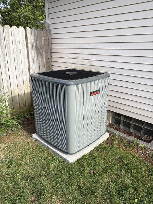 Completed full HVAC system replacement including indoor air handler and outdoor condensing unit. Installed new furnace and air handler assembly in basement utility area against existing cinder block wall, ensuring proper mounting and structural support. Routed white PVC condensate drain lines and venting pipes along left side of unit with professional organization. Connected black flexible conduit for electrical service between upper and lower components. Verified all manufacturer labels and safety warnings are visible and intact on equipment front panels. Established proper ductwork connections to existing metal supply plenum at ceiling level.

Positioned new outdoor condensing unit on level concrete pad adjacent to home foundation. Installed unit on stable mounting surface with adequate clearance from vinyl siding and basement window for proper airflow and future service access. Completed refrigerant line connections between indoor and outdoor components. Tested system startup, verif