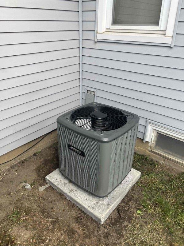 Completed full HVAC system replacement including outdoor condensing unit and indoor air handler. New condenser installed on concrete pad against exterior wall with proper clearance for airflow and service access, electrical conduit routed and connected per code. Indoor equipment installed in basement utility area with furnace integration, PVC condensate drainage piping, and flexible ductwork connections completed. System tested and verified operational.