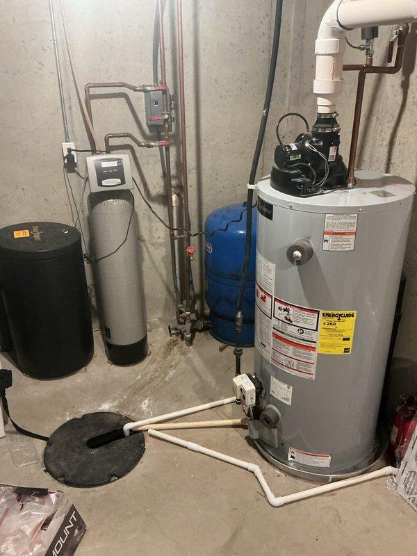Completed annual cooling maintenance on 9-year-old residential air conditioning system. Performed comprehensive tune-up inspection of Direct Comfort HVAC unit located in basement utility area, including visual assessment of furnace, condensate drainage system, and associated PVC piping configurations. Documented equipment condition through photographic record showing proper installation of water heater, water softener, pressure tank, and HVAC components with standard plumbing connections intact and operational.