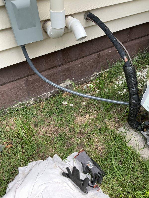 Responded to service call regarding exposed and damaged electrical conduits at outdoor air conditioning unit. Upon arrival, conducted visual inspection of the condensing unit and associated electrical connections. Confirmed conduit damage with exposed wiring vulnerable to weather intrusion. Documented existing conditions with photographs showing refrigerant line set, electrical connections, and compromised conduit routing along foundation. Verified air conditioning system remained operational despite cosmetic damage to protective conduit. Advised customer of potential water intrusion risks during precipitation events and recommended proper conduit repair and sealing to protect electrical connections from moisture damage and maintain code compliance.