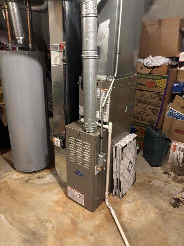 Completed full HVAC system installation including new Carrier furnace unit in basement utility area and exterior condensing unit on concrete pad. Installed vertical ductwork with proper metallic tape sealing, routed refrigerant lines and electrical conduit through exterior wall via PVC housing, and verified all connections between indoor and outdoor components. System commissioned and operational with proper airflow and refrigerant charge confirmed.
