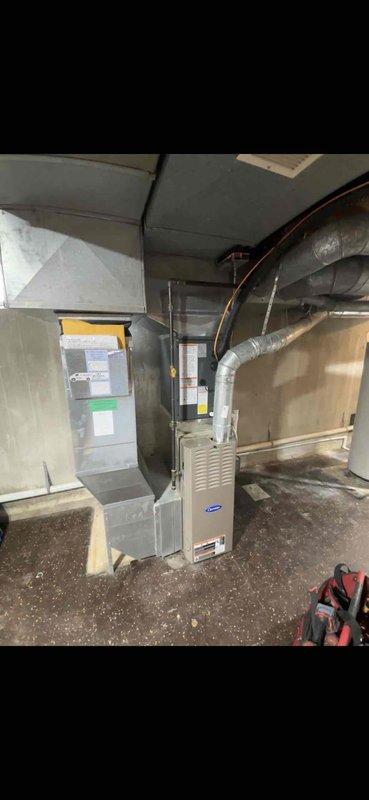 Completed full air conditioning system replacement including outdoor condensing unit and indoor air handler. Installed new Carrier outdoor unit on concrete pad against brick exterior wall with proper refrigerant line connections. Mounted new indoor air handler in basement mechanical room with integrated flexible ductwork and copper refrigerant lines properly routed through exposed joist space. System commissioned and verified operational.