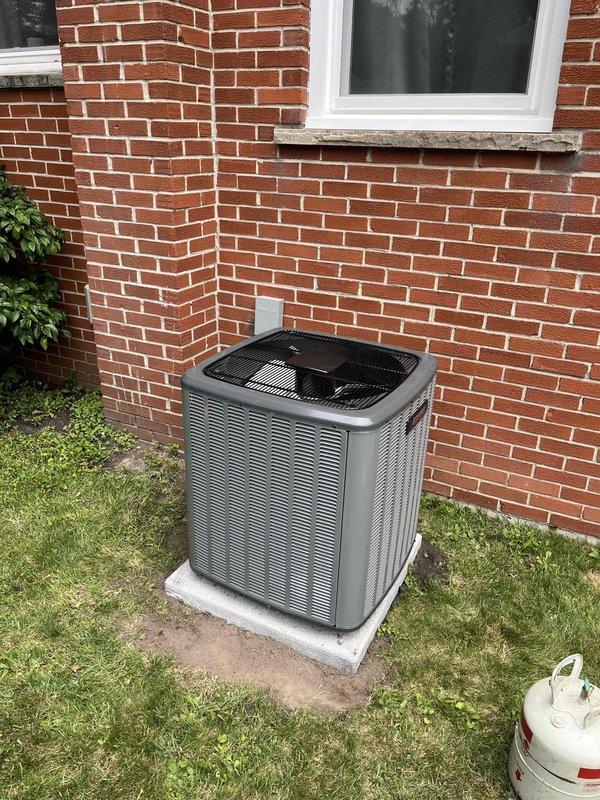 Completed full air conditioning system replacement including outdoor condensing unit and indoor air handler. Installed new Carrier outdoor unit on concrete pad against brick exterior wall with proper refrigerant line connections. Mounted new indoor air handler in basement mechanical room with integrated flexible ductwork and copper refrigerant lines properly routed through exposed joist space. System commissioned and verified operational.
