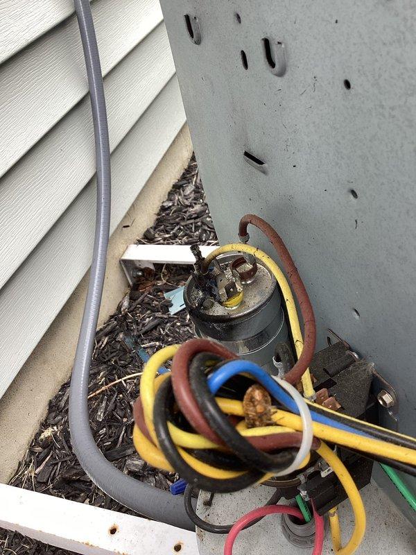 # Central Air Conditioning System - No Cooling Condition

Responded to service call for 2-year-old central air conditioning system with complete loss of cooling capacity. Upon arrival, performed visual inspection of outdoor condensing unit and indoor air handler components.

Exterior unit examination revealed significant accumulation of organic debris (leaves and plant material) in electrical component compartment and condensate drain pan area. Debris had collected around capacitor and electrical connections, creating potential for component failure and compromised system operation.

Documented equipment specifications from air handler nameplate: Model CV=2VA30172MGE4AA, Serial 3222J36511, utilizing TXV metering device and appropriate refrigerant type. Verified unit design pressures (625 PSIG high side, 310 kPa specifications) for reference during diagnostic procedures.

Inspected electrical connections at outdoor unit capacitor, noting multiple wire terminations (yellow, red, blue, gr