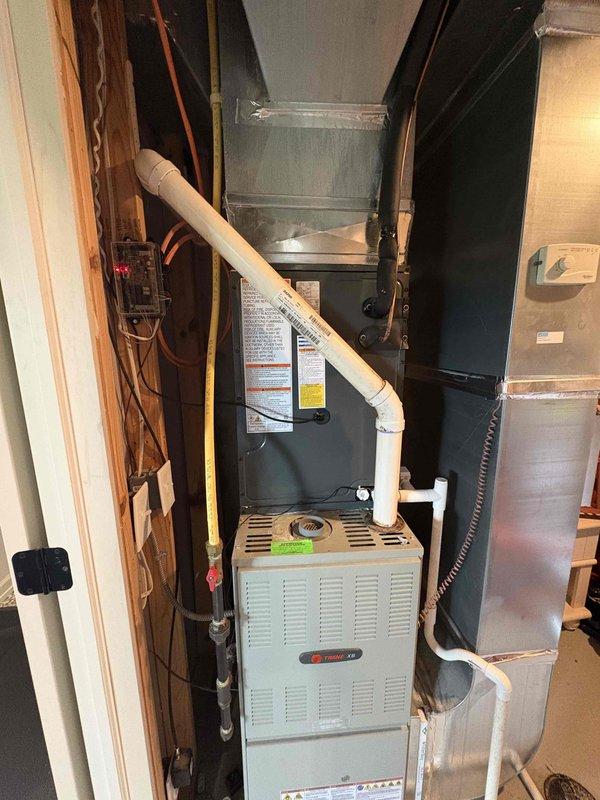 Completed full air conditioning system replacement including outdoor condenser unit and indoor air handler components. Installed new Trane equipment with proper refrigerant line connections, electrical conduit, condensate drainage via PVC piping, and integrated ductwork to existing furnace system. Mounted outdoor unit on concrete pad with gravel surround and verified all connections, airflow, and system operation per manufacturer specifications.