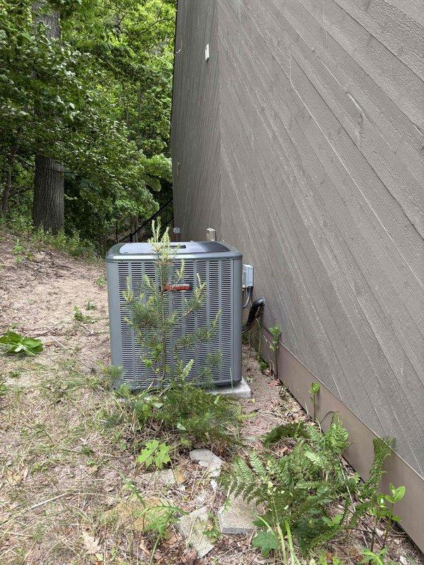 Completed full HVAC system installation including Bryant furnace and outdoor condensing unit. Furnace installed in basement utility area with proper PVC venting, ductwork connections, and air filtration system. Outdoor AC unit positioned on concrete pad adjacent to building exterior with appropriate clearances and refrigerant line connections established between indoor and outdoor components.