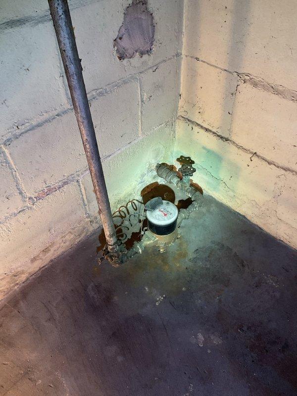 Responded to service call for main water supply valve in basement that would not shut off completely. Upon inspection, found heavily corroded gate valve located just before the water meter that had not fully closed for approximately 10-12 years, allowing water to continue trickling into the system when in closed position. Valve showed significant rust and age-related deterioration throughout the assembly. Assessed valve condition and determined replacement was necessary due to extent of corrosion and mechanical failure of internal gate mechanism. Replaced failed main shutoff valve with new brass ball valve, ensuring proper shutoff capability restored to main water supply line. Tested new valve operation multiple times to verify complete water shutoff with no residual flow. Photographed existing conditions showing rusted piping, water meter assembly, and evidence of long-term moisture exposure in the area. New valve now provides reliable shutoff control for the main water supply enterin