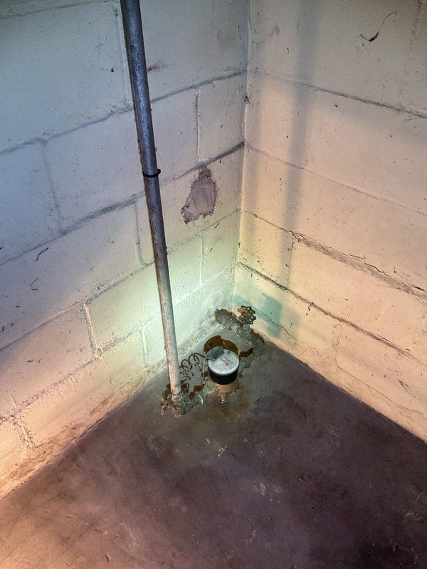 Responded to service call for main water supply valve in basement that would not shut off completely. Upon inspection, found heavily corroded gate valve located just before the water meter that had not fully closed for approximately 10-12 years, allowing water to continue trickling into the system when in closed position. Valve showed significant rust and age-related deterioration throughout the assembly. Assessed valve condition and determined replacement was necessary due to extent of corrosion and mechanical failure of internal gate mechanism. Replaced failed main shutoff valve with new brass ball valve, ensuring proper shutoff capability restored to main water supply line. Tested new valve operation multiple times to verify complete water shutoff with no residual flow. Photographed existing conditions showing rusted piping, water meter assembly, and evidence of long-term moisture exposure in the area. New valve now provides reliable shutoff control for the main water supply enterin