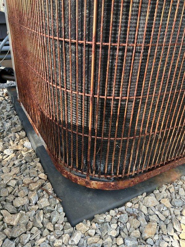 Completed annual cooling maintenance on Carrier outdoor condensing unit. Performed comprehensive system inspection, noting significant rust and corrosion on protective cage, support bands, and base components due to extended weather exposure. Cleaned condenser coils which showed dirt and debris accumulation between fins. Verified unit operational status, checked refrigerant levels, tested electrical connections, and confirmed proper airflow through heat exchanger. Documented equipment condition with photographs showing advanced deterioration of exterior metal surfaces and protective grille requiring future attention.