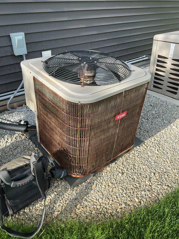 Completed annual cooling maintenance on Carrier outdoor condensing unit. Performed comprehensive system inspection, noting significant rust and corrosion on protective cage, support bands, and base components due to extended weather exposure. Cleaned condenser coils which showed dirt and debris accumulation between fins. Verified unit operational status, checked refrigerant levels, tested electrical connections, and confirmed proper airflow through heat exchanger. Documented equipment condition with photographs showing advanced deterioration of exterior metal surfaces and protective grille requiring future attention.