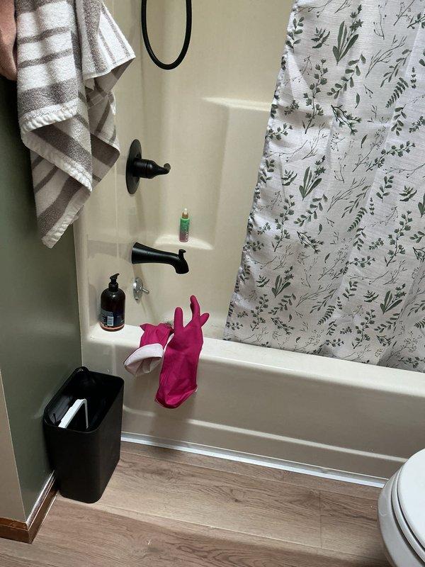 Conducted on-site assessment for bathtub enclosure installation and potential subfloor repair. Evaluated existing bathroom conditions including standard three-piece white acrylic tub surround with black plumbing fixtures, light wood-grain laminate flooring, and current shower curtain setup. Documented bathroom layout and measurements through photographic documentation to prepare comprehensive project estimate for tub enclosure replacement and subfloor evaluation.