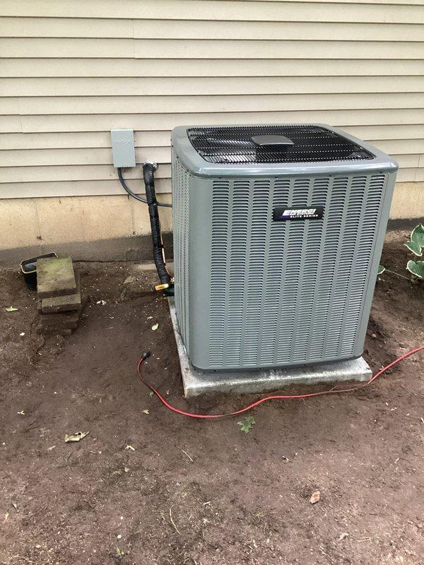 Completed full air conditioning system replacement including outdoor condenser unit installation on concrete pad with proper electrical connections and conduit routing. Unit was positioned adjacent to residential structure with secure mounting, junction box installation, and all necessary refrigerant line connections to existing ductwork infrastructure in basement area. System was tested and verified operational upon completion of same-day installation.