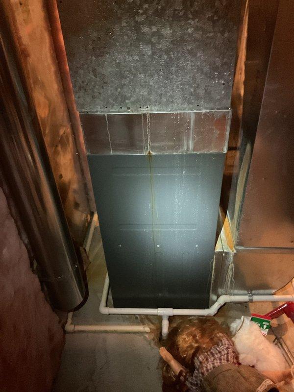 Responded to service call for reported refrigerant line leak at approximately 20-year-old air conditioning system. Upon inspection, accessed basement mechanical space and located the condensate drain line and refrigerant piping leading to outdoor AC unit. Extensive corrosion and rust damage was observed on metal ductwork and surrounding components, indicating prolonged moisture exposure in the area. Documented existing conditions with photographs showing deteriorated metal surfaces, PVC drain piping, copper refrigerant lines, and overall system configuration. The reported leak appears to be related to compromised piping connections or condensate drainage issues based on visible water damage patterns and mineral deposits on ductwork surfaces. Further diagnostic work and repair recommendations were provided to address the moisture intrusion and prevent additional system damage.