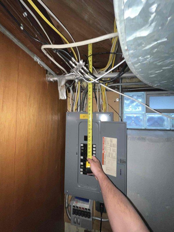 Conducted on-site assessment for new generator installation at approximately 50-year-old residential property. Evaluated existing electrical infrastructure in basement utility area, including main electrical panel with exposed circuit breakers and current metering equipment. Documented electrical service configuration, panel capacity, and available space for transfer switch installation. Photographed existing electrical system layout, wiring routing from panel through ceiling joists, and proximity to ductwork and structural components to determine optimal generator placement and connection points for estimate preparation.