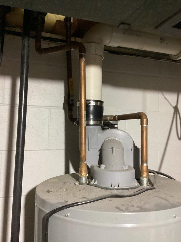 Responded to water heater leak complaint on 20-year-old residential unit. Upon inspection, identified minor leak originating from top connections of cylindrical tank-style water heater located in basement utility area. Documented existing plumbing configuration including copper supply lines, PVC venting system, and circulation pump assembly mounted to piping. Assessed condition of unit and photographed installation for service records. Provided client with findings and recommendations regarding aging water heater system.