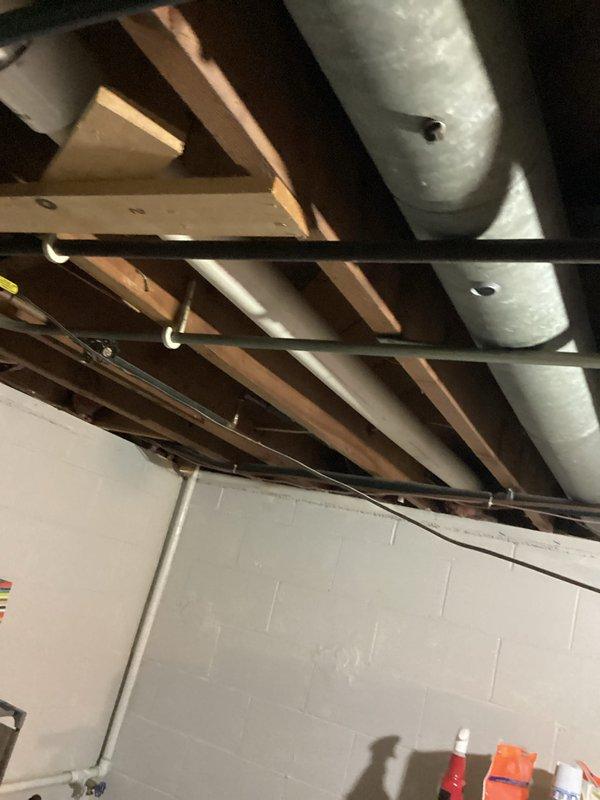 Responded to water heater leak complaint on 20-year-old residential unit. Upon inspection, identified minor leak originating from top connections of cylindrical tank-style water heater located in basement utility area. Documented existing plumbing configuration including copper supply lines, PVC venting system, and circulation pump assembly mounted to piping. Assessed condition of unit and photographed installation for service records. Provided client with findings and recommendations regarding aging water heater system.