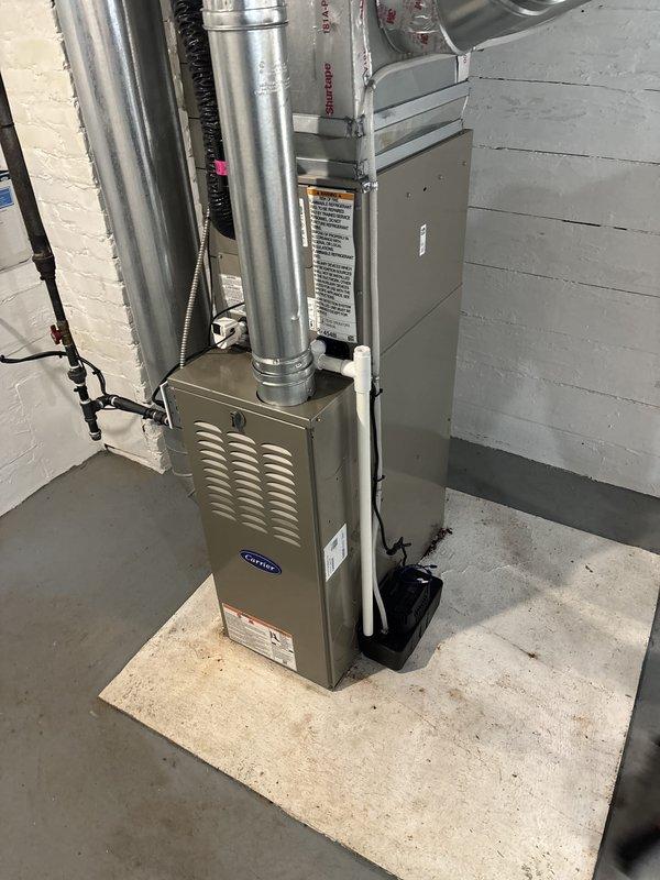 Completed full residential HVAC system installation including new Carrier furnace and Puron air conditioning condenser unit. Furnace installed in basement utility area with proper ductwork connections, ventilation components, and electrical conduit routing. Outdoor AC condenser positioned on level concrete pad in backyard with refrigerant lines and electrical disconnect box properly mounted to exterior wall. All components secured, labeled, and connected per manufacturer specifications.