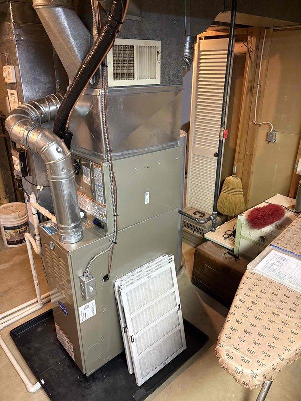 Completed full installation of Carrier brand furnace and air conditioning system in basement utility area. Unit was properly positioned on protective mat, all supply and return ductwork connected including metallic rigid ducts and flexible connections, PVC condensate drainage lines installed and routed appropriately, and new air filter installed in furnace cabinet. System installation verified with all components properly secured and operational.