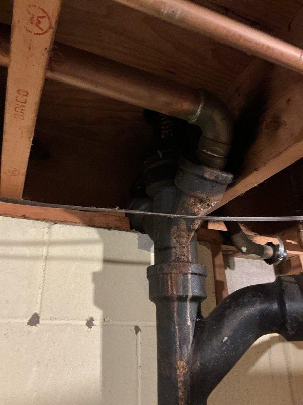 Responded to plumbing leak concern potentially originating from toilet connection or septic line. Upon inspection, discovered severely corroded cast iron waste piping and trap assembly in basement area. The vertical drain pipe and P-trap configuration exhibited extensive rust, oxidation, and surface deterioration throughout, with heavy corrosion visible on all metal components including fittings, cleanout plug, and connecting sections. The deteriorated condition of the iron piping presents significant risk for future leaks and potential failure. Documented existing plumbing infrastructure with photographs showing the extent of corrosion on both the vertical waste stack and trap assembly mounted against foundation wall. The rubber coupling connection at the trap inlet also shows age-related wear. Advised customer that the corroded cast iron drain system requires replacement to prevent imminent failure and water damage. Recommended scheduling pipe replacement with modern PVC drainage sys