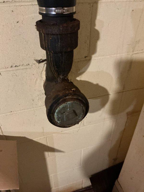Responded to plumbing leak concern potentially originating from toilet connection or septic line. Upon inspection, discovered severely corroded cast iron waste piping and trap assembly in basement area. The vertical drain pipe and P-trap configuration exhibited extensive rust, oxidation, and surface deterioration throughout, with heavy corrosion visible on all metal components including fittings, cleanout plug, and connecting sections. The deteriorated condition of the iron piping presents significant risk for future leaks and potential failure. Documented existing plumbing infrastructure with photographs showing the extent of corrosion on both the vertical waste stack and trap assembly mounted against foundation wall. The rubber coupling connection at the trap inlet also shows age-related wear. Advised customer that the corroded cast iron drain system requires replacement to prevent imminent failure and water damage. Recommended scheduling pipe replacement with modern PVC drainage sys