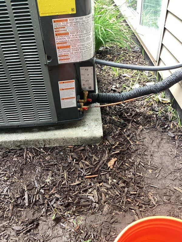 Successfully completed full air conditioning system replacement at residential property. Removed existing outdoor condensing unit and installed new HVAC condenser on concrete pad adjacent to exterior wall with white siding. Ran new refrigerant lines from unit to structure, secured electrical conduit and wiring to exterior wall, and installed disconnect box per code requirements. Unit positioned in landscaped side yard area with proper clearances maintained. All electrical connections completed, system tested, and verified operational. Installation includes proper labeling and safety documentation affixed to equipment.