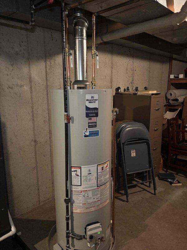Successfully installed a 40-gallon natural gas water heater in the basement utility area. The installation included a Bradford White tall model unit with proper venting through a metallic vent pipe system, copper supply lines with brass shut-off valves and compression fittings on both the hot and cold water sides, and all required labeling and safety compliance stickers. The unit was positioned on a stable concrete floor against the foundation wall with adequate clearance for service access and proper connection to existing gas and water supply lines.