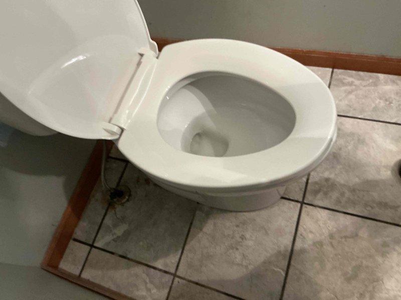 Responded to main bathroom toilet with cracked tank causing active water spillage. Upon arrival, assessed the toilet and confirmed tank damage requiring replacement. Documented existing conditions with photos showing the two-piece toilet installation on tile flooring and verified the extent of the leak to prevent further water damage to the surrounding area.