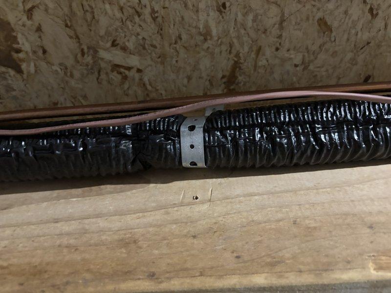 Responded to customer complaint of loud banging noise from outside AC unit upon startup. Inspected exterior condensing unit and traced refrigerant lines into attic space. Found inadequately secured suction line creating vibration and impact noise against floor joists when compressor engaged. Repositioned and properly secured copper refrigerant line and associated flex duct using appropriate mounting straps and clamps to eliminate contact with structural framing members. Cycled system multiple times to verify noise elimination and proper operation.