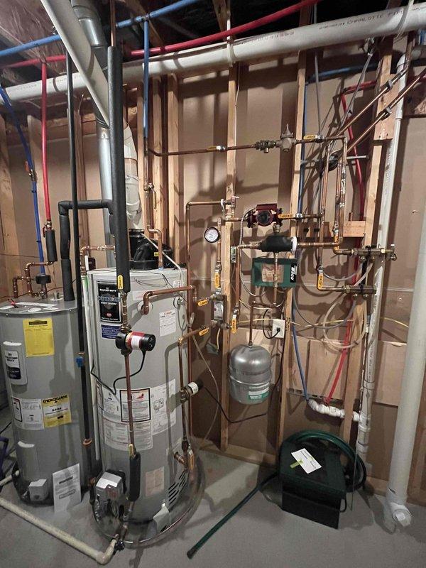Responded to water heater leak in drain pan. Upon inspection, found an 11-year-old Bradford White water heater (Model M150T6FBN, 67,000 BTU natural gas, installed May 2015) with active leaking into the collection pan beneath the unit. Given the age of the water heater and presence of leak, documented the existing installation including all plumbing connections, expansion tank, circulation pump, copper piping, PEX connections, and associated mechanical components. Photographed the unit's specification label and overall system configuration for assessment and future reference.