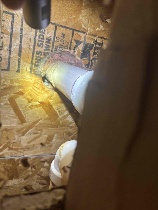 Technician returned to property to complete access work in basement closet space. Opened and accessed confined crawl space area with PVC plumbing infrastructure, including drain and vent piping with elbow connections installed between floor joists. Work completed within estimated timeframe, with photo documentation of existing pipe configuration and installation conditions in the enclosed space.
