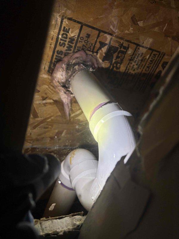 Technician returned to property to complete access work in basement closet space. Opened and accessed confined crawl space area with PVC plumbing infrastructure, including drain and vent piping with elbow connections installed between floor joists. Work completed within estimated timeframe, with photo documentation of existing pipe configuration and installation conditions in the enclosed space.