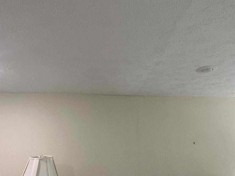 Responded to plumbing leak complaint originating from outdoor hose bib penetrating into interior living space. Upon inspection, identified water intrusion affecting ceiling and wall surfaces in residential living area. Documented conditions with photographs showing ceiling staining and interior damage to walls adjacent to exterior hose connection point, assessed leak source and provided customer with findings and repair recommendations.