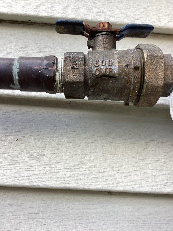 Responded to plumbing leak at 22-year-old residential property where issue began one day prior. Upon inspection, located broken pipe at exterior ball valve assembly mounted on building exterior near utility meter. Valve showed significant weathering, corrosion, and age-related deterioration with rust visible at stem connection point. Repaired/replaced damaged section and verified proper valve operation. Documented conditions with photographs showing exterior plumbing configuration, valve assembly with 600 WP rating markings, and connection points against vinyl siding. Confirmed repair resolved active leak and restored system integrity.