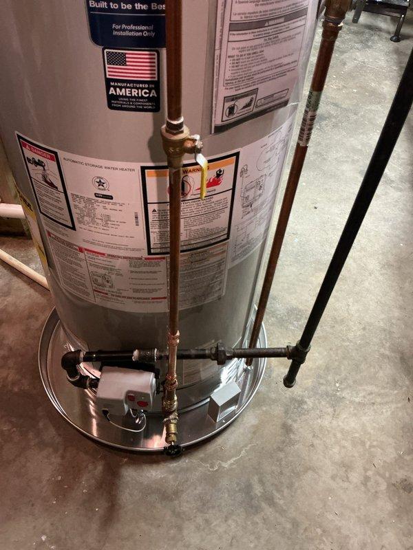Completed installation of 50-gallon natural gas water heater in basement utility area. Unit was properly positioned on concrete floor with drain pan, connected copper supply lines with brass fittings to inlet and outlet ports, installed black expansion tank on top of unit, and verified all plumbing connections were secure and leak-free. All manufacturer specifications, safety labels, and code requirements were confirmed during installation.