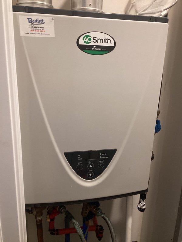 Responded to no hot water complaint on five-year-old A.O. Smith tankless water heater. Upon inspection, found unit experiencing complete failure to produce hot water. Performed descaling maintenance procedure using cleaning solution to remove mineral buildup from heat exchanger, as evidenced by the turquoise descaling fluid and service equipment visible during the process. Flushed system through copper service lines, cleared scale deposits, and restored unit to proper operating condition. Tested all connections and verified hot water delivery restored to normal function.