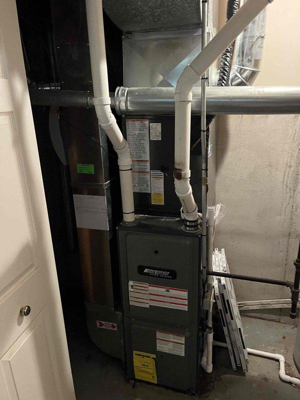 Completed full HVAC system replacement in residential mechanical room. Removed existing failed air conditioning equipment and installed new green furnace unit with corresponding gray air handler. Configured white PVC venting system with proper vertical routing for exhaust and intake. Connected flexible ductwork to air handler and verified all duct connections secure. Installed condensate drain lines with appropriate pitch and termination points. Mounted both units on concrete floor in side-by-side configuration for optimal space utilization. Verified all manufacturer labels and safety warnings properly displayed on equipment. System tested and confirmed operational upon completion.