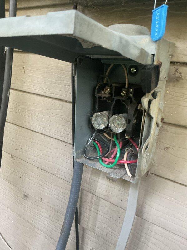 Responded to a no cooling call and performed diagnostic inspection of outdoor heat pump unit and electrical disconnect. Upon arrival, inspected outdoor unit which showed normal external condition with typical outdoor debris accumulation on top panel. Verified fan guard and housing integrity were intact. Examined electrical disconnect box mounted on exterior wall, confirmed fuse holders and internal wiring connections were present with proper color-coded conductors. Unit components appeared functional with no visible damage to electrical enclosure or outdoor equipment housing.