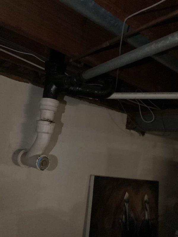 Responded to a drainage issue in the basement utility area. Inspected the white PVC drain line mounted along the ceiling joists and placed a collection container on the floor to capture water from a leak or overflow condition. Monitored the drainage system to ensure proper function and prevent water damage to the surrounding area.