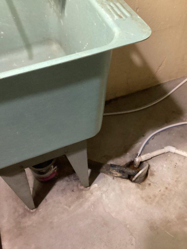 Responded to a drainage issue in the basement utility area. Inspected the white PVC drain line mounted along the ceiling joists and placed a collection container on the floor to capture water from a leak or overflow condition. Monitored the drainage system to ensure proper function and prevent water damage to the surrounding area.