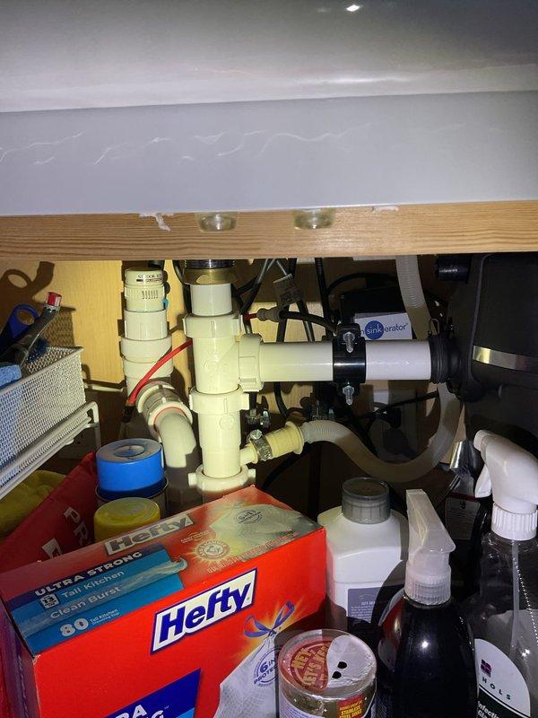 Performed diagnostic evaluation of residential water softener system and documented existing plumbing configuration. Inspected under-sink plumbing connections including garbage disposal unit and PVC drainage system to assess potential water supply issues. Examined water filtration system with pressurized storage tank and four-stage filter cartridge assembly mounted in utility area, verifying connections and component condition. Documented system layout with photographs for scheduled follow-up repair work requiring 1-2 hours to complete necessary adjustments and restore proper water softener operation.