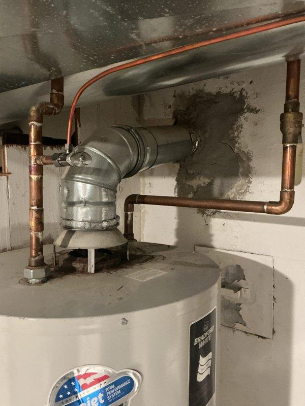 Provided comprehensive estimate for water heater replacement options on 15-year-old 65-gallon conventional tank unit showing signs of age and deterioration. Evaluated existing installation including venting configuration, copper supply lines with foam insulation, and surrounding area exhibiting moisture damage and wall staining. Presented comparison pricing for both tankless conversion system and traditional tank water heater replacement, documenting current conditions through photographic assessment.