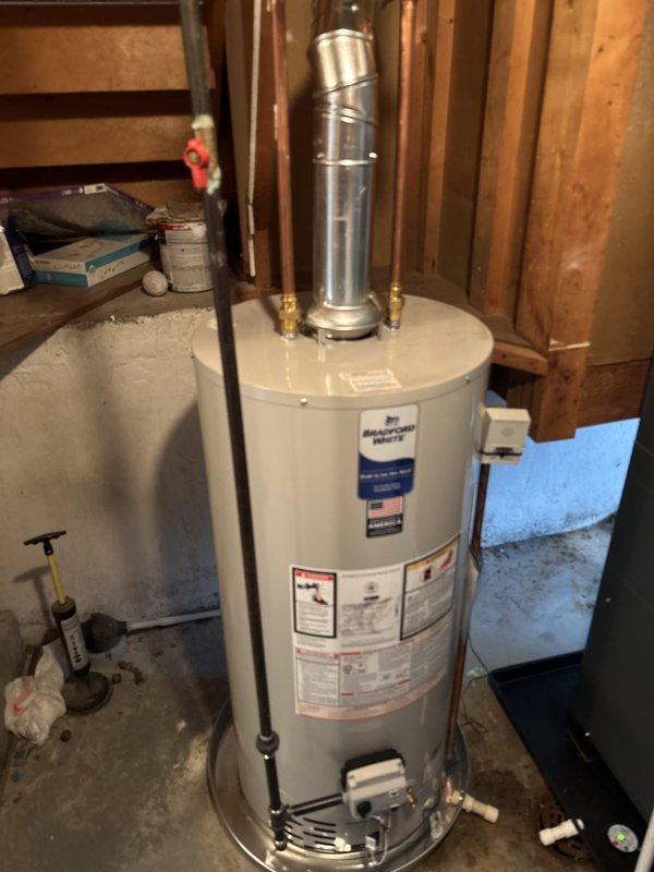 Completed full installation of residential HVAC system and water heater in basement utility area. Installed gray metal dual-compartment furnace unit with proper venting using white PVC exhaust pipes on both sides and black flexible ductwork connection at top. Mounted and connected silver metallic air conditioning components adjacent to furnace. Installed white cylindrical water heater with metallic vertical vent pipe, brass fittings, and proper copper and PVC piping connections. All equipment positioned on concrete floor with appropriate clearances, manufacturer specification labels visible and accessible, and venting systems properly terminated. Michigan Saves financing documentation processed and submitted through DocuSign for project approval. System installation completed per manufacturer specifications with all safety requirements met and equipment operational.