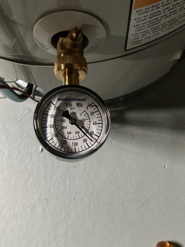 Responded to service call for 4-year-old water heater producing loud "boom boom" pressure noise lasting approximately 15 minutes after hot water usage. Inspected unit and installed pressure gauge at drain valve to diagnose suspected pressure-related issue. Gauge readings confirmed excessive pressure buildup during heating cycle, indicating thermal expansion without proper relief. No active leaks or loss of hot water capacity observed. Documented equipment condition with photographs showing water heater installation, pressure monitoring equipment, and surrounding plumbing configuration including water treatment system and copper supply lines. Advised customer of findings and recommended solutions to eliminate noise condition caused by thermal expansion in closed plumbing system.