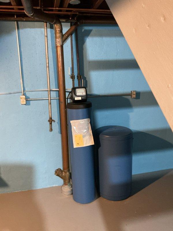 Responded to service call for 4-year-old water heater producing loud "boom boom" pressure noise lasting approximately 15 minutes after hot water usage. Inspected unit and installed pressure gauge at drain valve to diagnose suspected pressure-related issue. Gauge readings confirmed excessive pressure buildup during heating cycle, indicating thermal expansion without proper relief. No active leaks or loss of hot water capacity observed. Documented equipment condition with photographs showing water heater installation, pressure monitoring equipment, and surrounding plumbing configuration including water treatment system and copper supply lines. Advised customer of findings and recommended solutions to eliminate noise condition caused by thermal expansion in closed plumbing system.