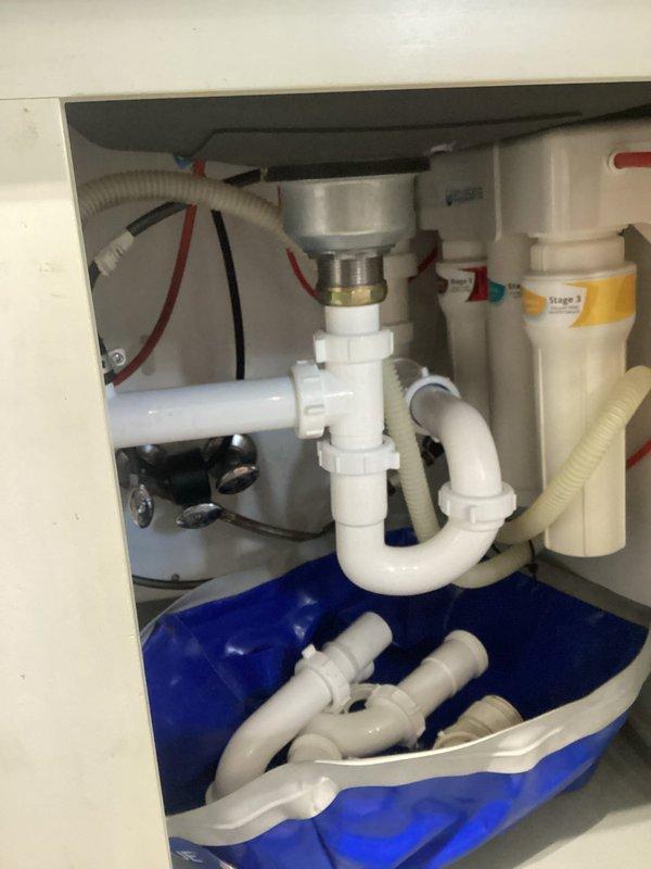 Reattached kitchen sink and reconnected plumbing assembly following countertop replacement. Reinstalled P-trap drainage system, garbage disposal connections, and water supply lines, ensuring all fittings were properly secured and leak-free. Verified proper operation of all components upon completion.