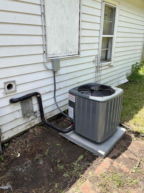 Completed full air conditioning system replacement at residential property. Removed existing AC unit and installed new cylindrical condenser unit on concrete pad against exterior wall with proper clearances. Ran new black flexible conduit along exterior wall to electrical disconnect box, securing all lines with appropriate mounting brackets. System startup performed, verified proper refrigerant charge, electrical connections, and airflow. All components tested and operational within manufacturer specifications.