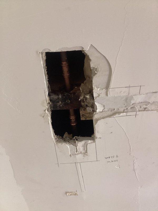 Responded to active plumbing leak causing water intrusion through kitchen ceiling in 1960s-era home. Upon arrival, accessed affected area by cutting openings in ceiling to expose copper supply lines. Located leak at pipe fitting connection between parallel vertical copper pipes. Repaired faulty connection and secured plumbing system. Documented existing conditions and completed repairs with photographic evidence showing exposed copper piping, structural framing, and access points created for repair work.