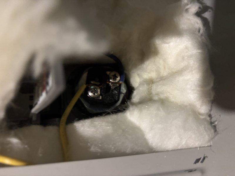 Completed warranty repair work on electrical outlet junction box. Replaced damaged elements and properly installed insulation around electrical connections, ensuring all wiring terminals and connections were secure and code-compliant. Verified proper installation of electrical components with appropriate fiberglass insulation placement around the recessed junction box cavity.