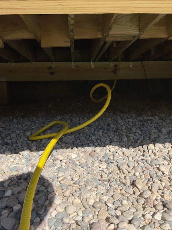 Installed gas line split to accommodate two grills at residential property. Ran flexible gas line through landscaped area and beneath deck structure, ensuring proper connection and code-compliant installation for dual grill operation.
